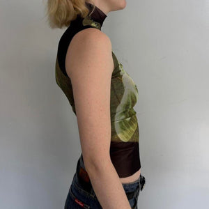 Side view of model wearing lime slice mesh asymmetrical top with sheer black mock neck detail, Y2K graphic sleeveless fitted tank top, trendy women’s going out top styled with denim skirt.