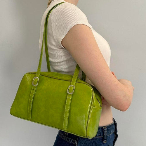 Lime green Y2K shoulder bag, glossy baguette purse with adjustable buckle straps, trendy 2000s aesthetic handbag styled with white ribbed tee and denim jeans, statement street style accessory for women