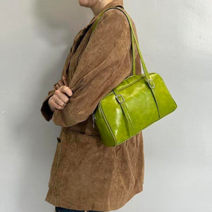 Lime green Y2K shoulder bag, glossy mini baguette purse with adjustable buckle straps, vintage-inspired 2000s handbag styled with brown suede jacket, trendy retro street style accessory, statement women’s shoulder bag