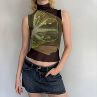 Model wearing lime slice mesh asymmetrical top with sheer black mock neck overlay, Y2K graphic sleeveless going out top styled with denim mini skirt, trendy women’s streetwear fashion outfit.