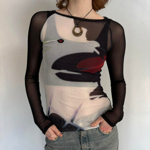 Close-up front view of black sheer mesh graphic top for women with long sleeves, fitted stretchy Y2K going out top, abstract print cool girl blouse, trendy boutique fashion shirt paired with denim jeans, sheer streetwear top.