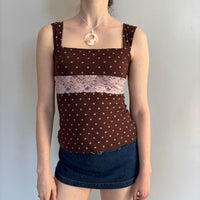 Brown polka dot lace tank top with blush pink floral lace panel, square neckline, and fitted silhouette styled with a dark wash denim mini skirt. Feminine coquette-inspired Y2K top perfect for soft girl outfits, vintage-inspired fashion, Pinterest aesthetic looks, and everyday casual styling.