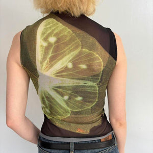 Back view of model wearing lime slice mesh asymmetrical top with sheer black mock neck overlay, Y2K graphic sleeveless fitted tank top, trendy women’s streetwear going out top styled with denim skirt.