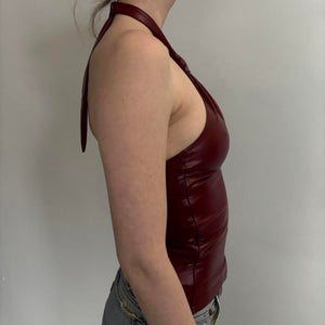 Burgundy faux leather halter tank top featuring a tie-back neckline, fitted bodycon shape, glossy finish, stylish Y2K fashion, trendy going-out top, date night outfit, and modern women’s statement clothing.
