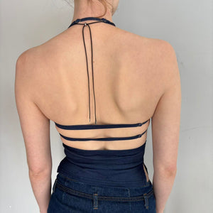 Back view of navy blue Y2K halter top with open back and strappy detailing, adjustable tie halter neck, fitted backless tank top on model, minimalist aesthetic going out top, stretchy bodycon halter top paired with denim, trendy 2000s inspired women’s fashion