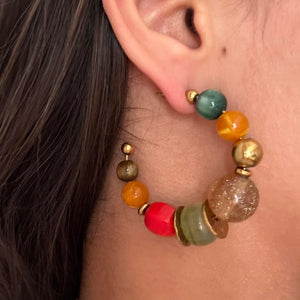 Close-up of colorful chunky beaded hoop earrings featuring oversized multicolor resin beads, glossy statement accents, and gold hardware in a retro-inspired design. Trendy Y2K statement earrings with eclectic cool girl aesthetic, perfect for Pinterest fashion, vacation outfits, artsy jewelry styling, and bold IT girl accessories.