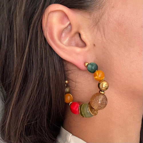Colorful beaded hoop earrings featuring chunky multicolor resin beads and gold accents in a bold retro-inspired design. Trendy Y2K statement earrings with coastal cool girl aesthetic, perfect for Pinterest fashion, vacation outfits, eclectic jewelry styling, and artsy IT girl looks.