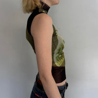 Side view of model wearing lime slice mesh asymmetrical top with sheer black mock neck detail, Y2K graphic sleeveless fitted tank top, trendy women’s going out top styled with denim skirt.