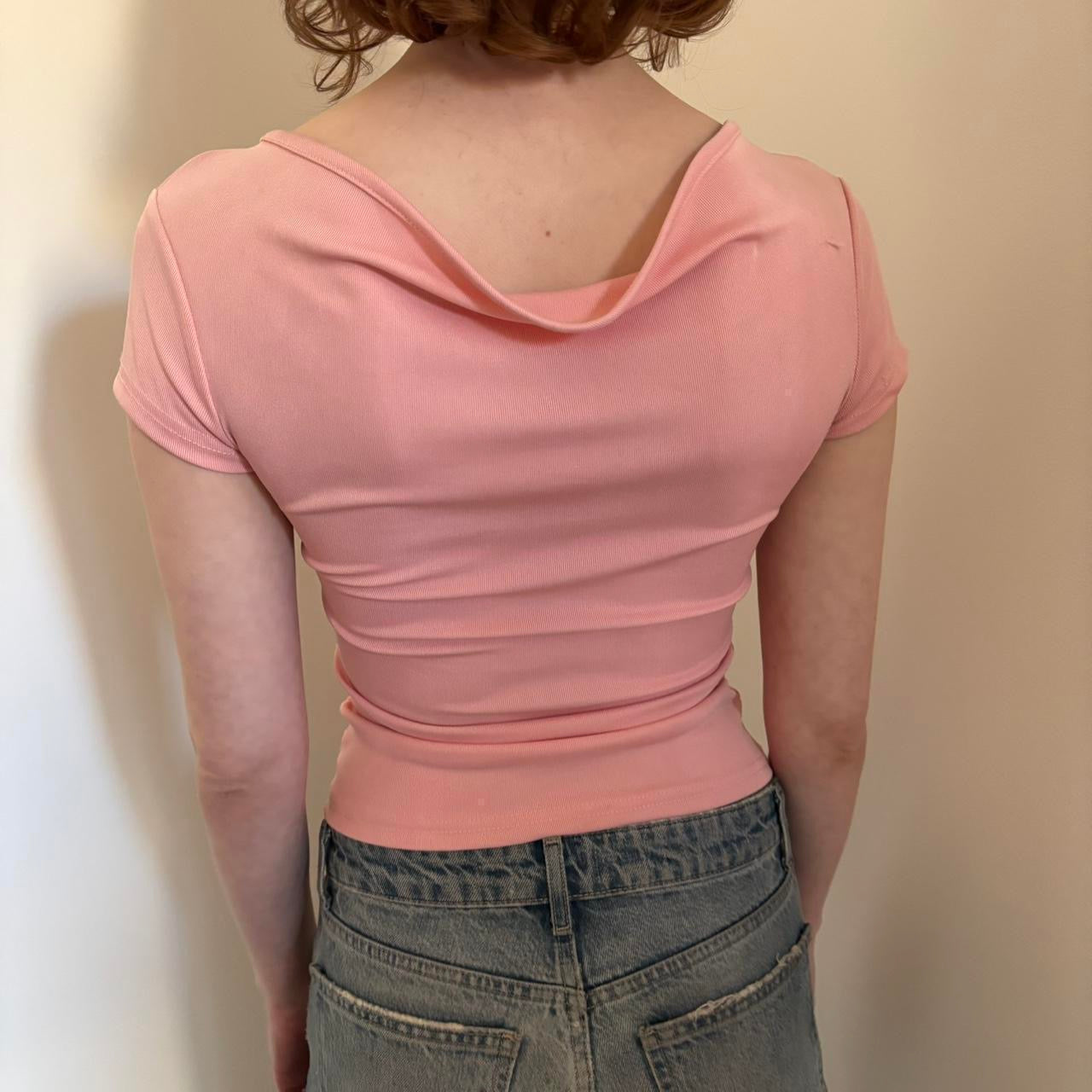 Back view of pink fitted baby tee top for women, stretchy Y2K crop top aesthetic, slim fit short sleeve pastel pink shirt, trendy coquette style casual top paired with low rise denim jeans, minimal boutique fashion look.