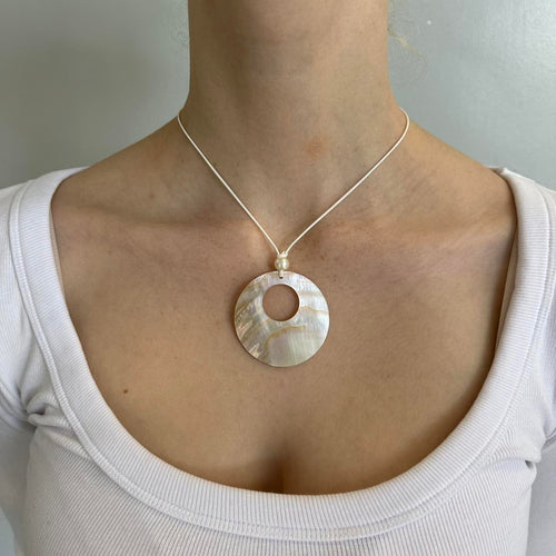 Mother of pearl circle pendant necklace on a minimalist cord chain featuring an iridescent shell design and coastal clean girl aesthetic. Trendy Y2K inspired pendant jewelry perfect for beachy outfits, Pinterest fashion, and everyday minimalist styling.