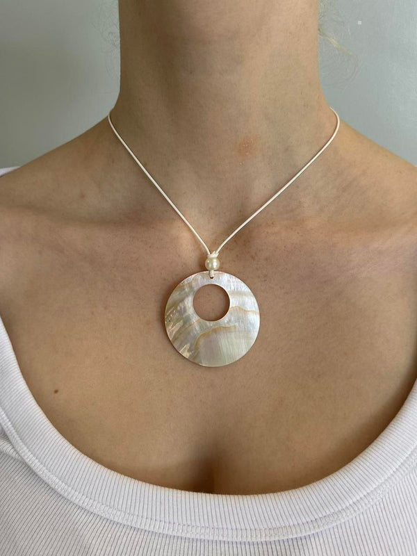 Mother of pearl circle pendant necklace on a minimalist cord chain featuring an iridescent shell design and coastal clean girl aesthetic. Trendy Y2K inspired pendant jewelry perfect for beachy outfits, Pinterest fashion, and everyday minimalist styling.