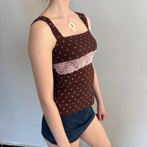 Side view of a brown polka dot lace camisole top with a square neckline and blush pink floral lace panel. Feminine coquette aesthetic tank top styled with a mini denim skirt and mother of pearl pendant necklace. Soft girl, Y2K-inspired, vintage-inspired fitted cami perfect for casual outfits, date night looks, cottagecore fashion, and trendy Pinterest-style wardrobes.