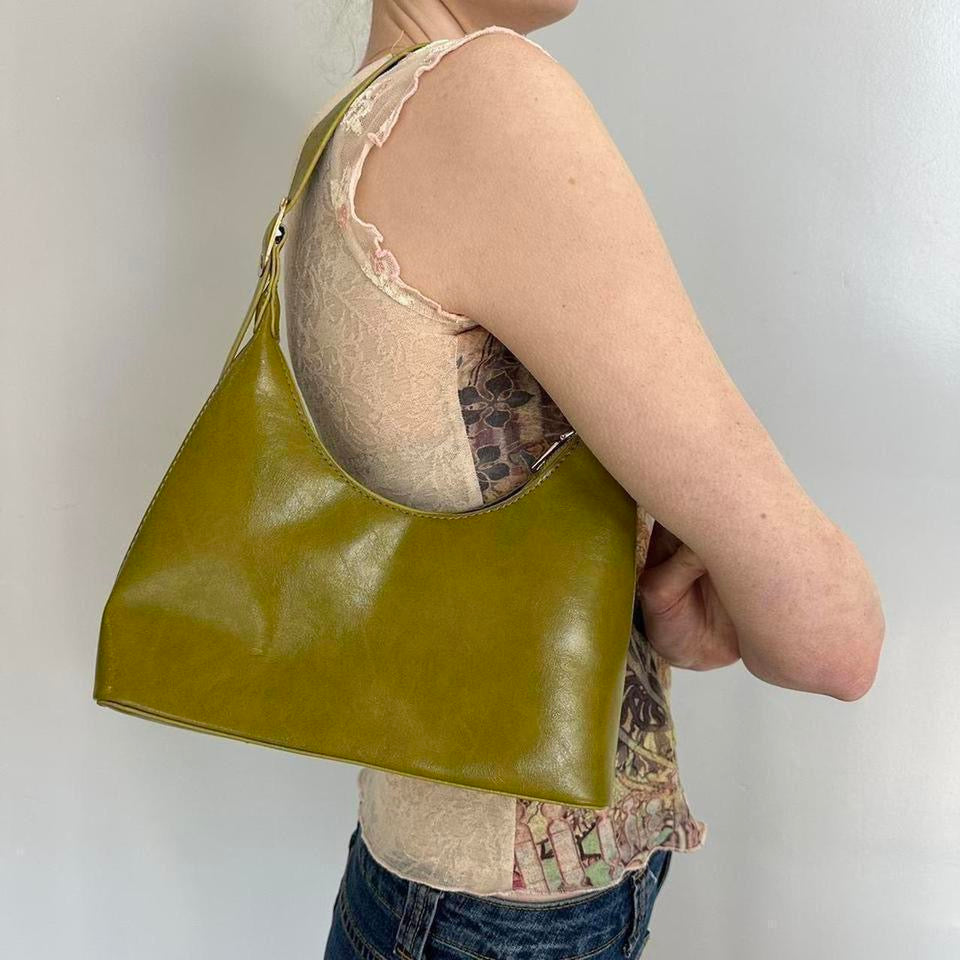 Olive green faux leather shoulder bag styled on model, featuring a sleek minimalist silhouette and Y2K-inspired design. Trendy olive handbag perfect for everyday wear, casual outfits, vintage fashion, clean girl aesthetic, minimalist style, and modern it-girl wardrobes. Spacious hobo purse with a chic underarm fit and timeless fashion appeal.