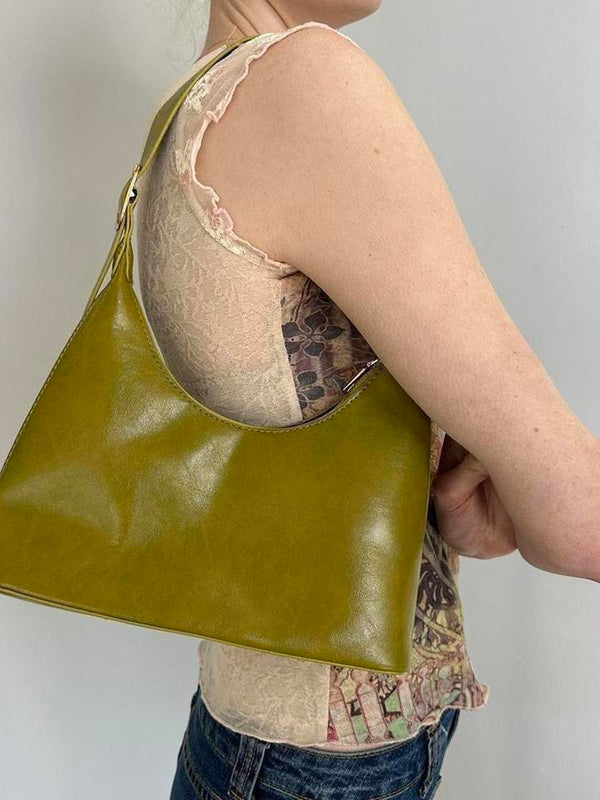 Olive green faux leather shoulder bag styled on model, featuring a sleek minimalist silhouette and Y2K-inspired design. Trendy olive handbag perfect for everyday wear, casual outfits, vintage fashion, clean girl aesthetic, minimalist style, and modern it-girl wardrobes. Spacious hobo purse with a chic underarm fit and timeless fashion appeal.