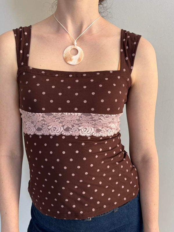 Brown polka dot lace tank top with pink floral lace trim, square neckline, and adjustable tie-back detail. Feminine coquette-inspired Y2K cami top styled with a mother of pearl pendant necklace, perfect for soft girl, vintage-inspired, and Pinterest aesthetic outfits.
