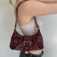 Burgundy faux leather shoulder bag styled on model, vintage-inspired Y2K handbag with silver buckle detail, trendy cherry red purse, slouchy 2000s shoulder bag, aesthetic IT girl accessory, everyday faux leather handbag for streetwear and going-out outfits
