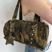 Close-up of a Y2K camouflage shoulder bag featuring silver hardware, ring accents, stud details, and a matching camo charm. Vintage-inspired canvas handbag with an army green camouflage print and structured silhouette. Trendy camo purse perfect for streetwear fashion, grunge outfits, everyday wear, Pinterest-inspired style, downtown It Girl aesthetics, concerts, travel, and casual Y2K looks.