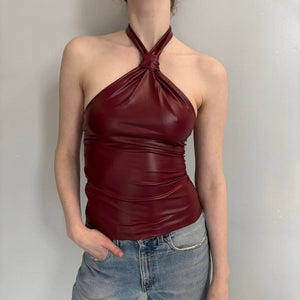 Burgundy faux leather halter neck top for women with a twisted front detail, sleek fitted silhouette, wine red party top, date night outfit, trendy Y2K clothing, and fashionable going-out top with a glossy leather-look finish.
