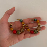 Colorful chunky beaded hoop earrings featuring multicolor resin-style beads with gold accents in a bold retro-inspired design. Trendy Y2K statement earrings with eclectic coastal cool girl aesthetic, perfect for Pinterest fashion, vacation outfits, artsy jewelry styling, and playful IT girl accessories.