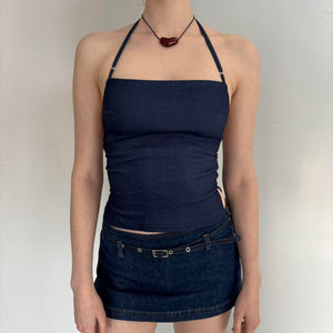 Navy blue Y2K halter top outfit with denim mini skirt, fitted backless tank top on model, minimalist aesthetic summer look, adjustable strap halter top paired with low-rise denim skirt, trendy going out outfit for women, 2000s inspired fashion style