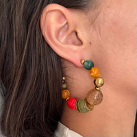 Colorful beaded hoop earrings featuring chunky multicolor resin beads and gold accents in a bold retro-inspired design. Trendy Y2K statement earrings with coastal cool girl aesthetic, perfect for Pinterest fashion, vacation outfits, eclectic jewelry styling, and artsy IT girl looks.